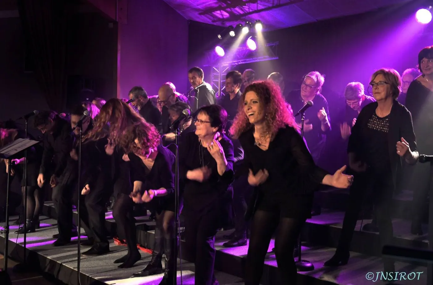 Choristes en noir qui chantent et bougent sous les lumières violettes